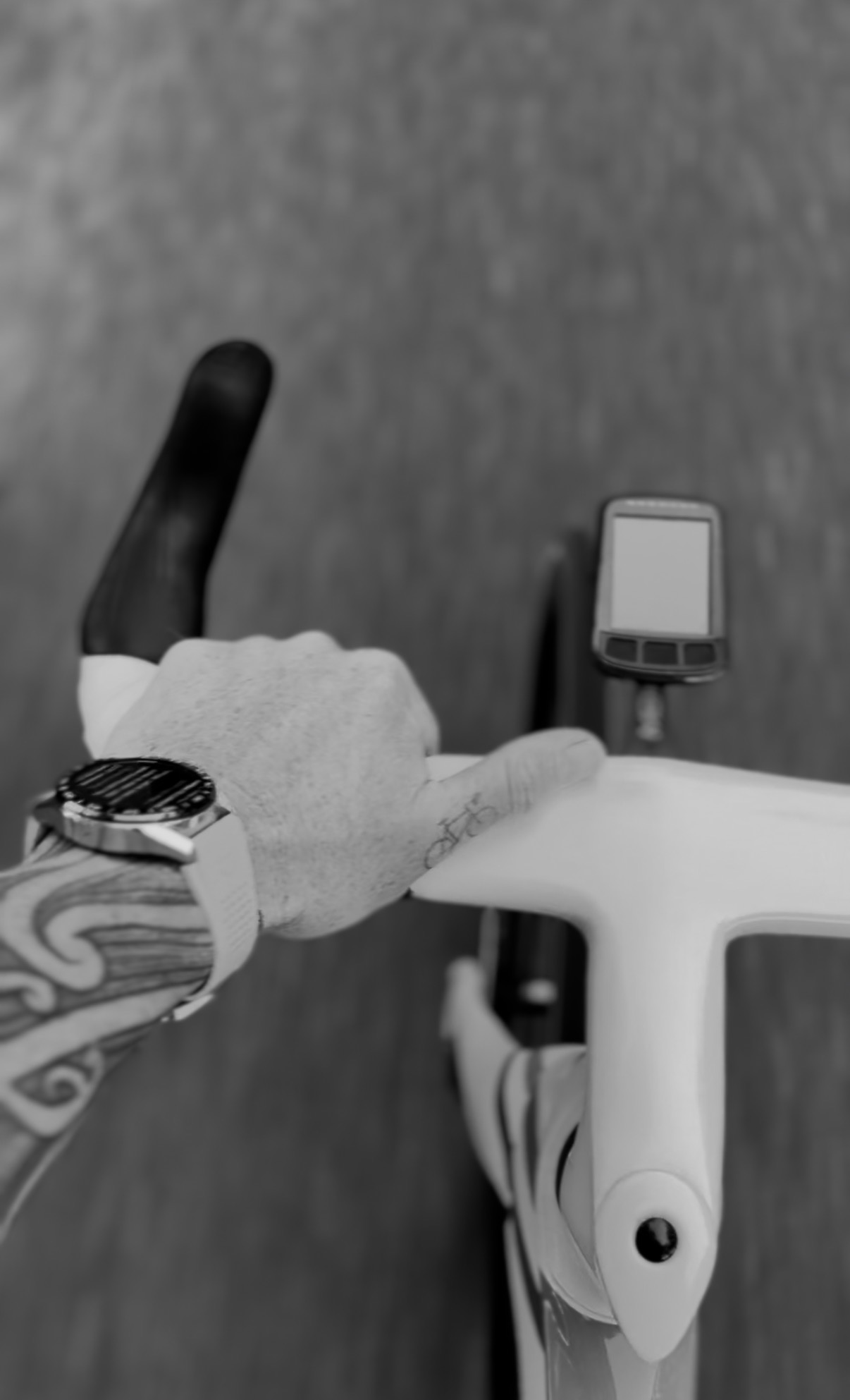 A hand resting on the bars of a road bike with the cycling computer screen switched off