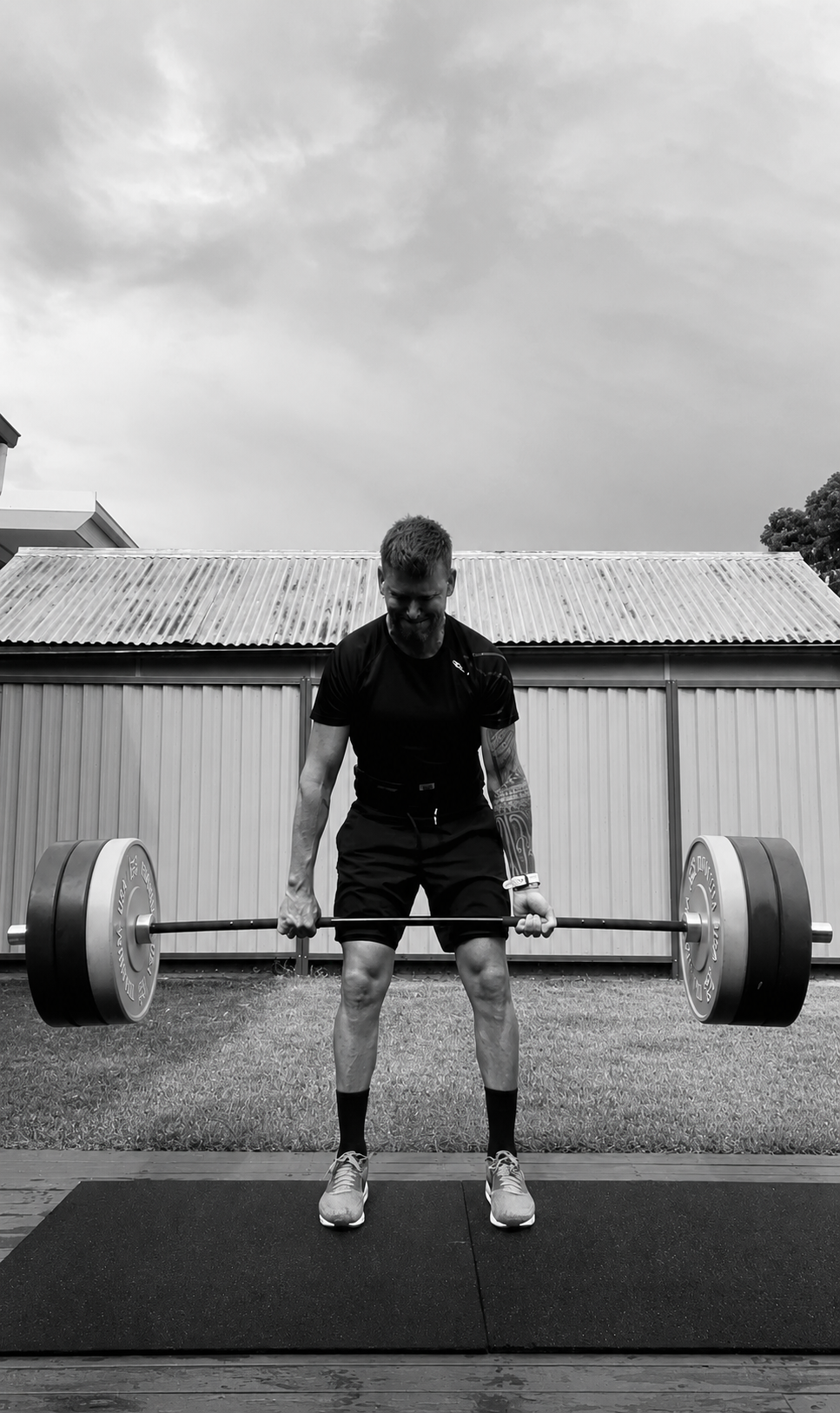 Phillipe performing a deadlift in a home gym, black and white